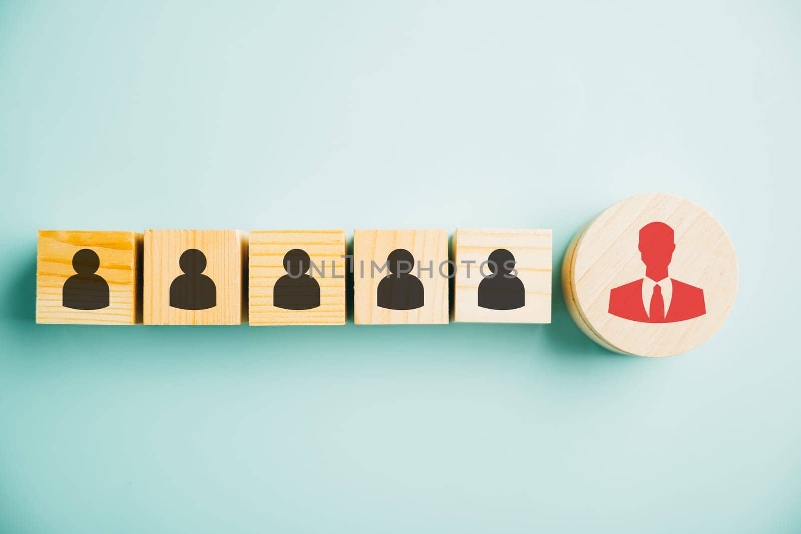 Red manager icon prominently standing out from set of staff employee icons printed on wooden block. concept of different thinking, talent development, and role of leadership in corporate environment.