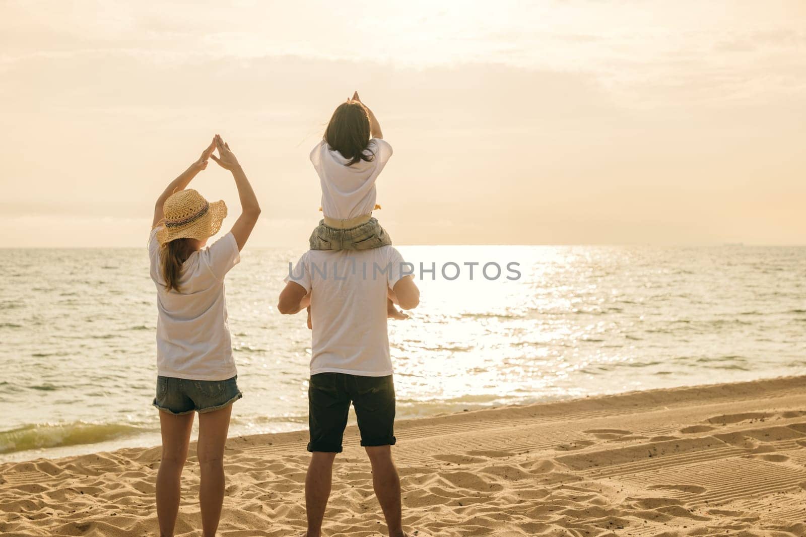 Happy family in holiday. Father, Mother and kids having fun together shoulder ride on summer beach, Parents carrying children on neck at beach, family is enjoying their summer in sunset time