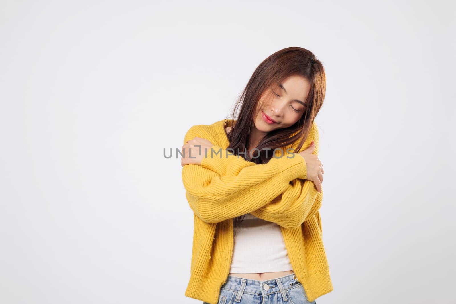 Hug yourself with ease, hug your heart with warmth. A confident Asian woman embraces herself, showing relaxation and gentle joy in a quiet, carefree moment. isolated white background
