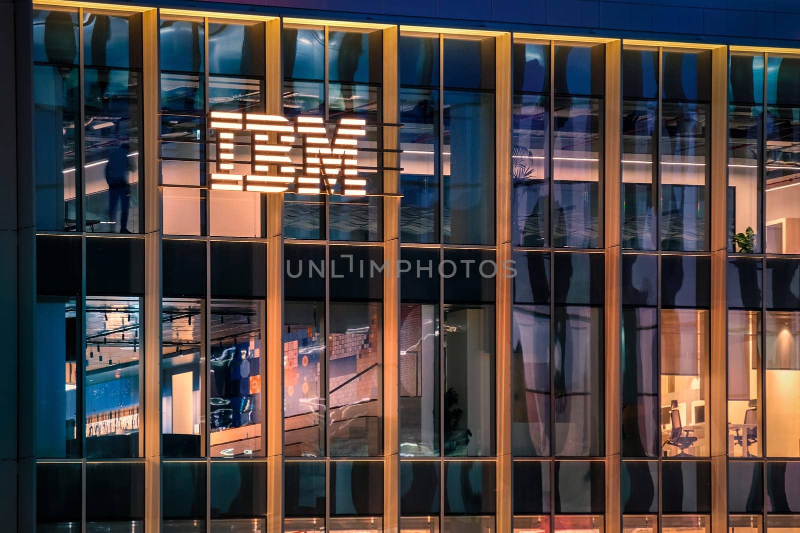 Jan 15, 2025 - Lisbon, Portugal: Nighttime view of IBM office building with glowing logo and sleek glass exterior. Illuminated interior spaces and reflections, innovative spirit and global presence of renowned technology corporation, corporate life