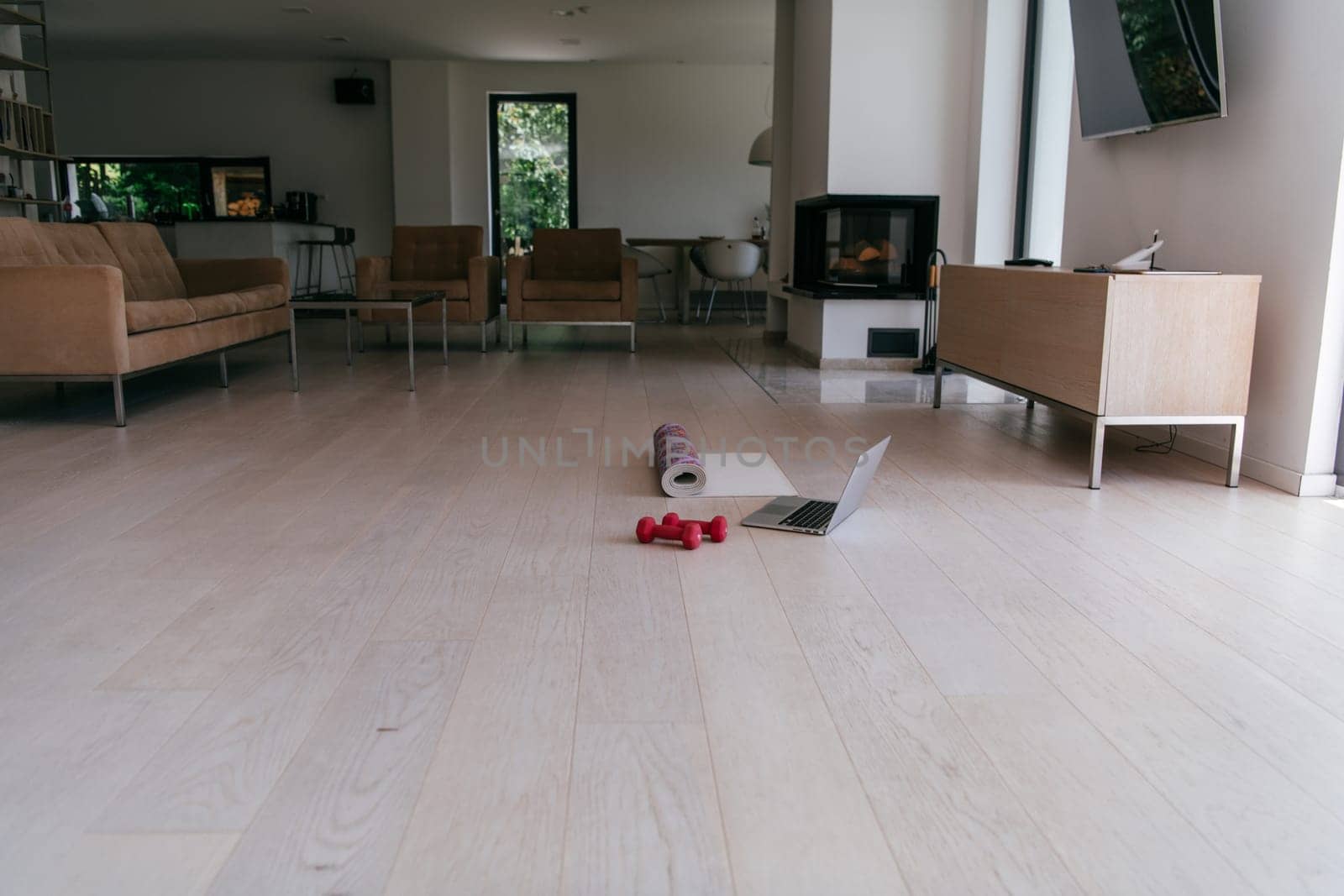 Photo of a laptop, dumbbells and headphones on the floor of the living room. Online training concept.