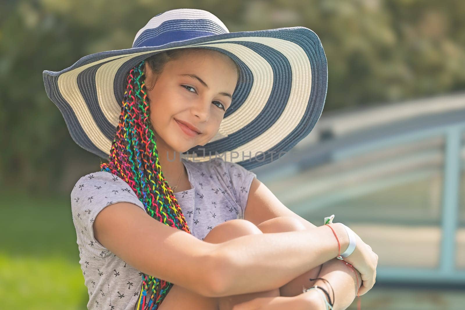 Happy cute little girl is posing in a straw hat at the garden . Horizontally. 
