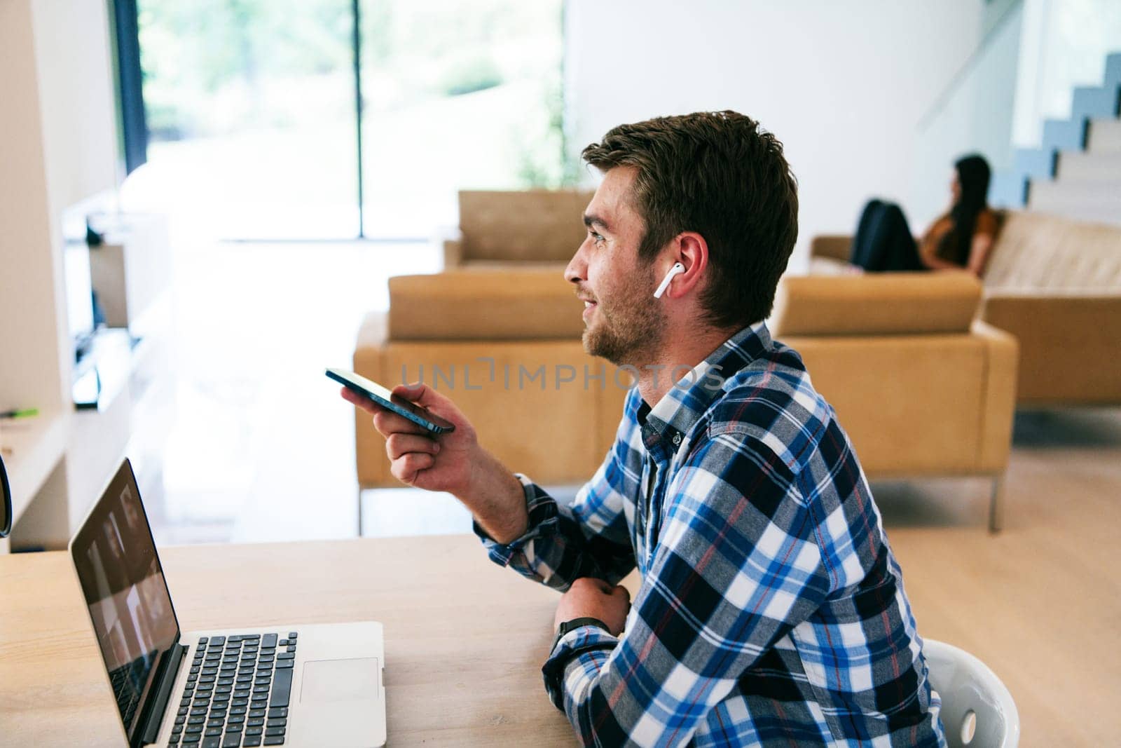 A freelancer sitting at a table in a modern living room, with headphones using a laptop for business video chat, conversation with friends and entertainment.