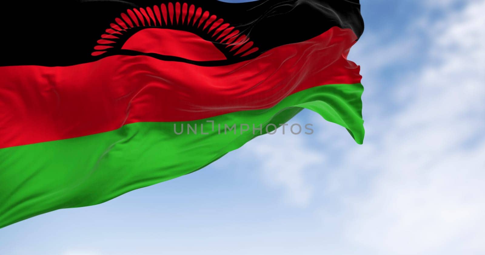 Close-up of Malawi national flag waving in the wind on a clear day. Black, red, green stripes with a rising sun in black. 3d illustration render. Rippling fabric