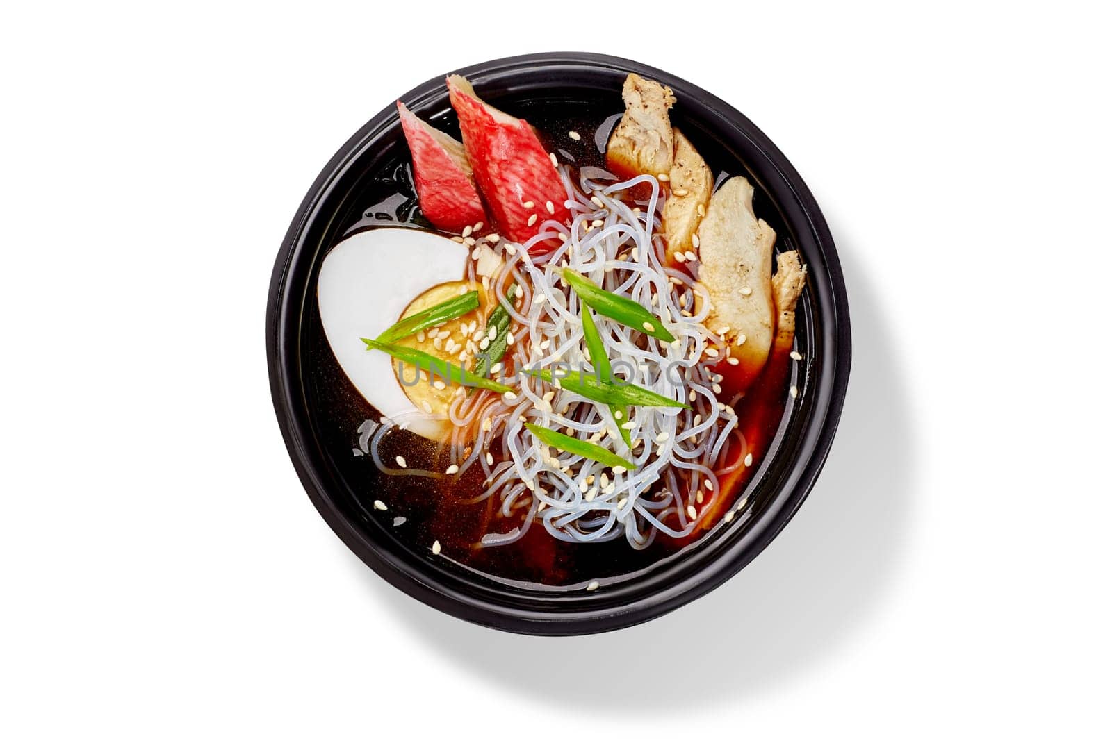 Delicious asian soup with chicken, shirataki noodles, egg, sesame seeds and green onions served in a black bowl