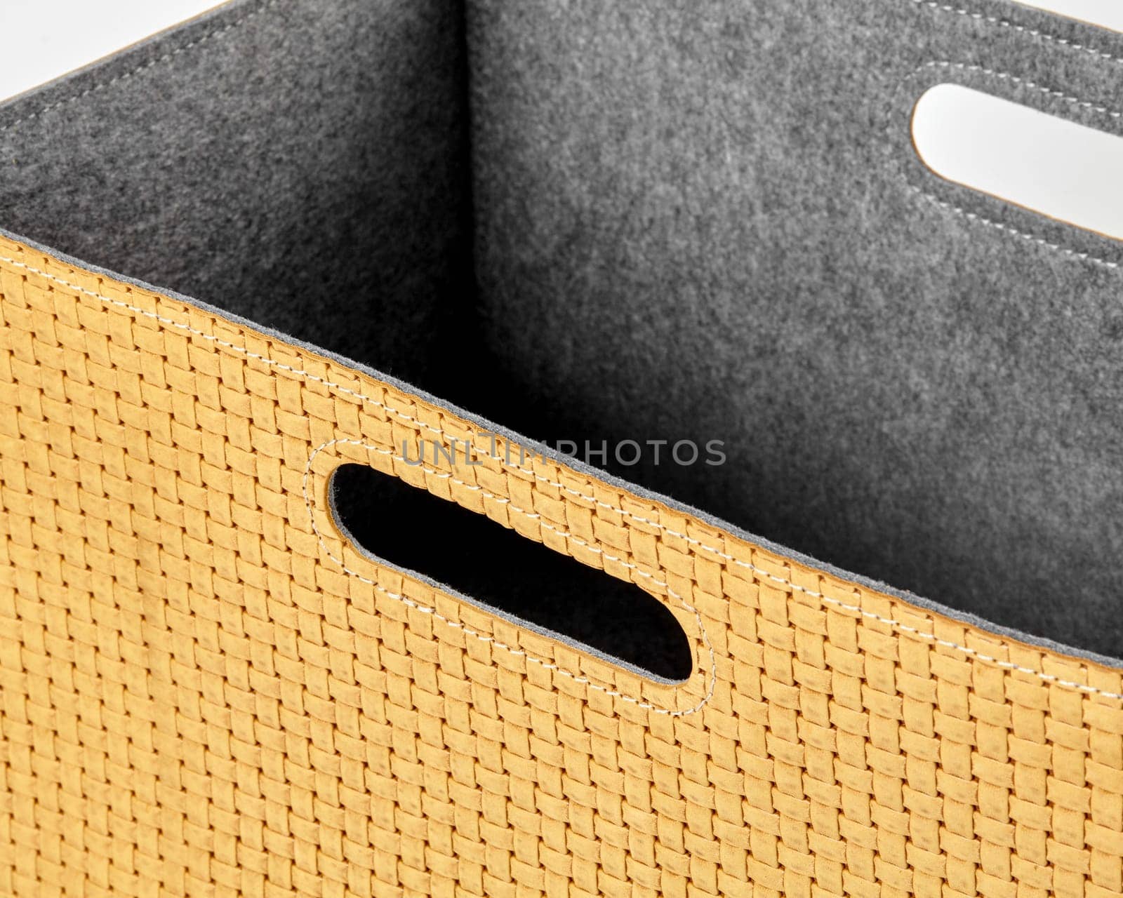 Close-up of an empty yellow woven storage box with grey felt lining and convenient carry handles