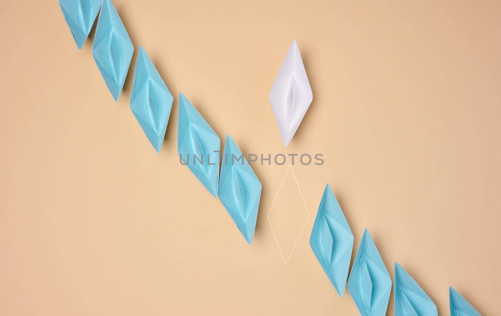 A line of blue origami paper boats with one white and the outline of the missing one, symbolizing uniqueness or a missing element, are placed on a neutral background