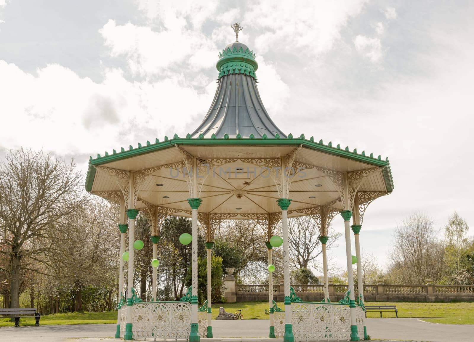Newcastle, UK - Apr 13, 2025 - View of A Bandstand And A Grandstand. It’s a modern replica of the Victorian bandstand that had been installed in the Leazes park. The Music Pavilion with Green trees in the background, use it as your Wallpaper, Poster and Space for text, Selective focus.