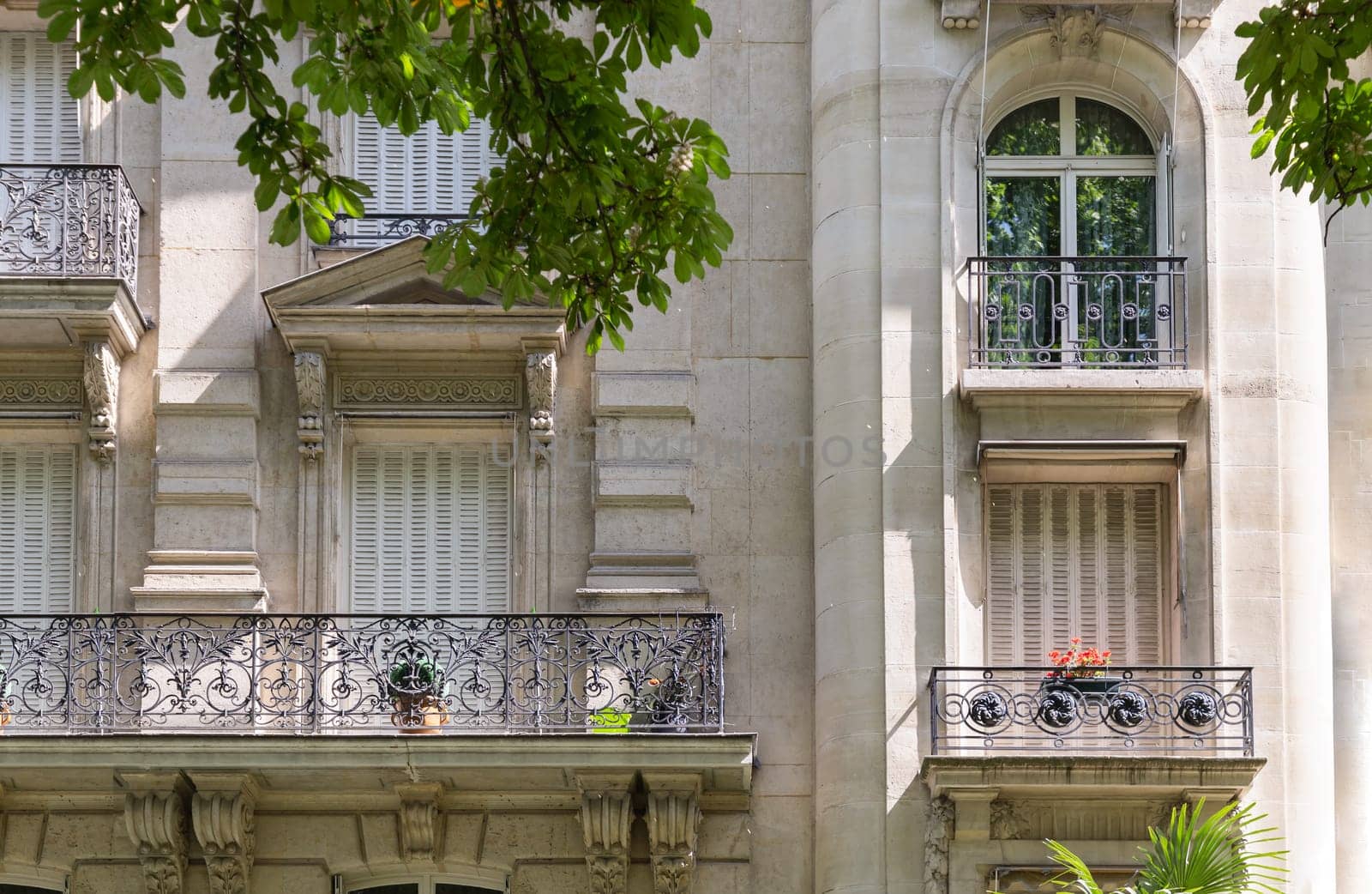 France, Paris - May 03, 2025 - Architecture splendour of Traditional French residential tenement building with Traditional French Shutters & Windows and wrought iron black railings balconies located in the center of Paris. Facade of the Parisian building. use it as your Wallpaper, Poster and Copy space, Selective focus.
