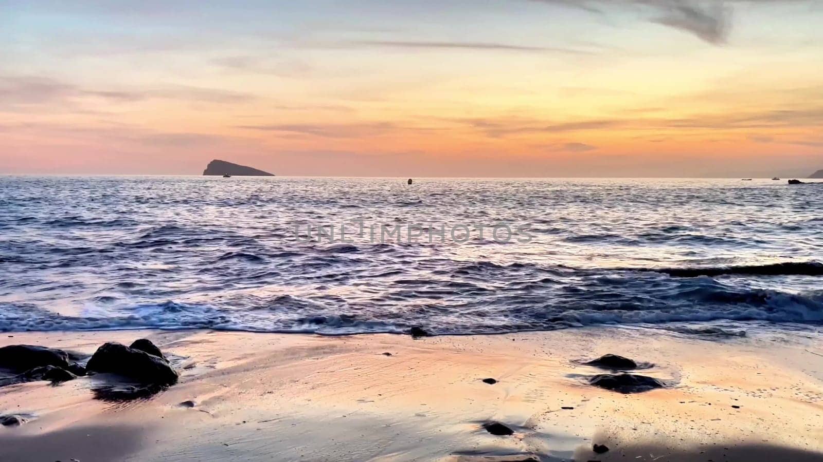 A beautiful and tranquil beach scene at sunset showcasing gentle waves, perfect for relaxation amid a rocky coastline