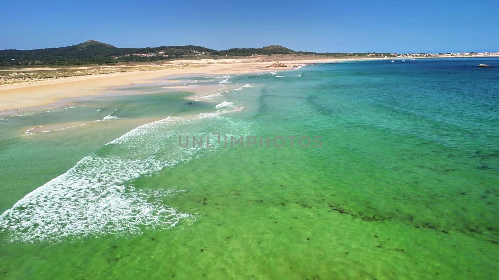 This aerial view beautifully showcases a tranquil beach featuring mesmerizing turquoise waters and soft golden sands