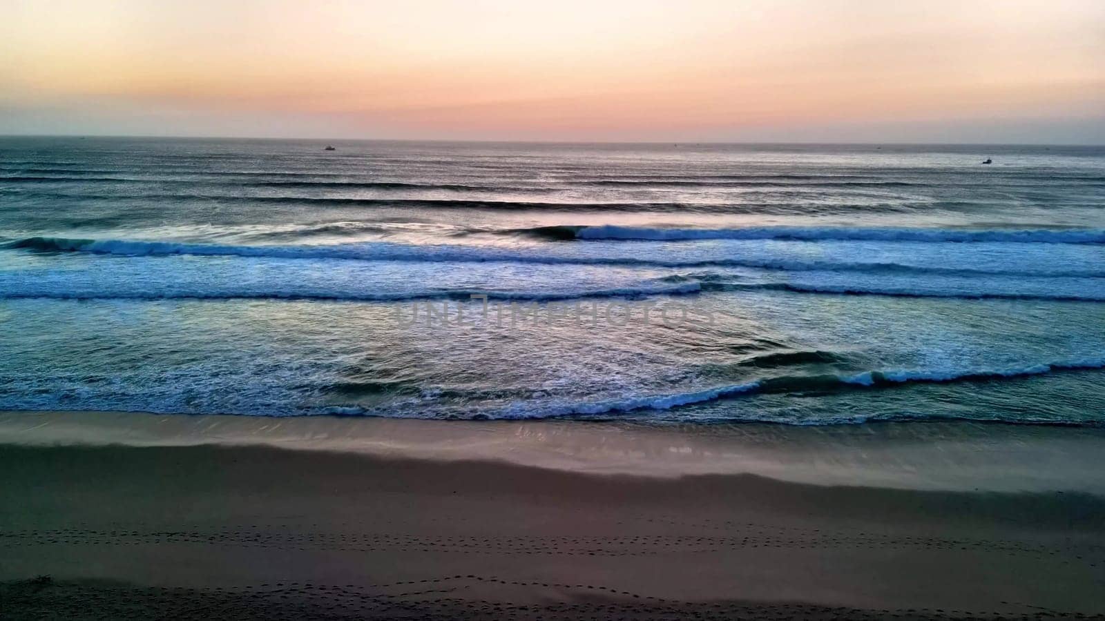 A breathtakingly captivating view of gentle ocean waves gently rolling under a picturesque sunset sky