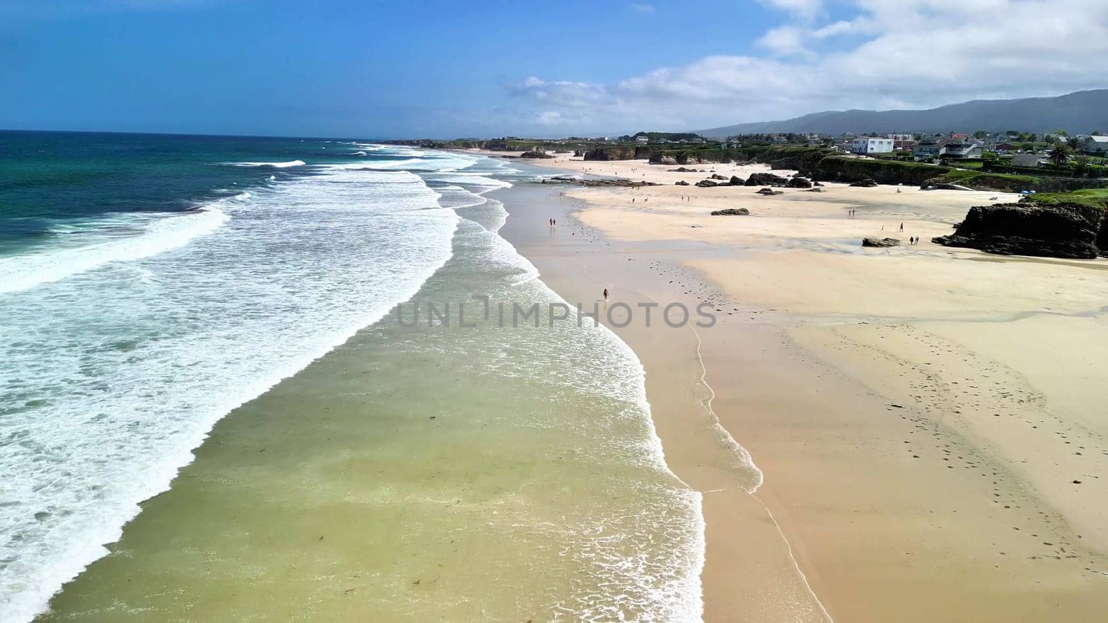 Experience a stunning aerial view of a serene beach showcasing gentle waves, soft golden sand, and clear blue skies