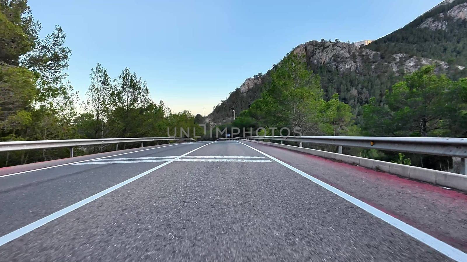 A beautiful winding road in a breathtaking mountainous landscape with vibrant trees and clear blue skies