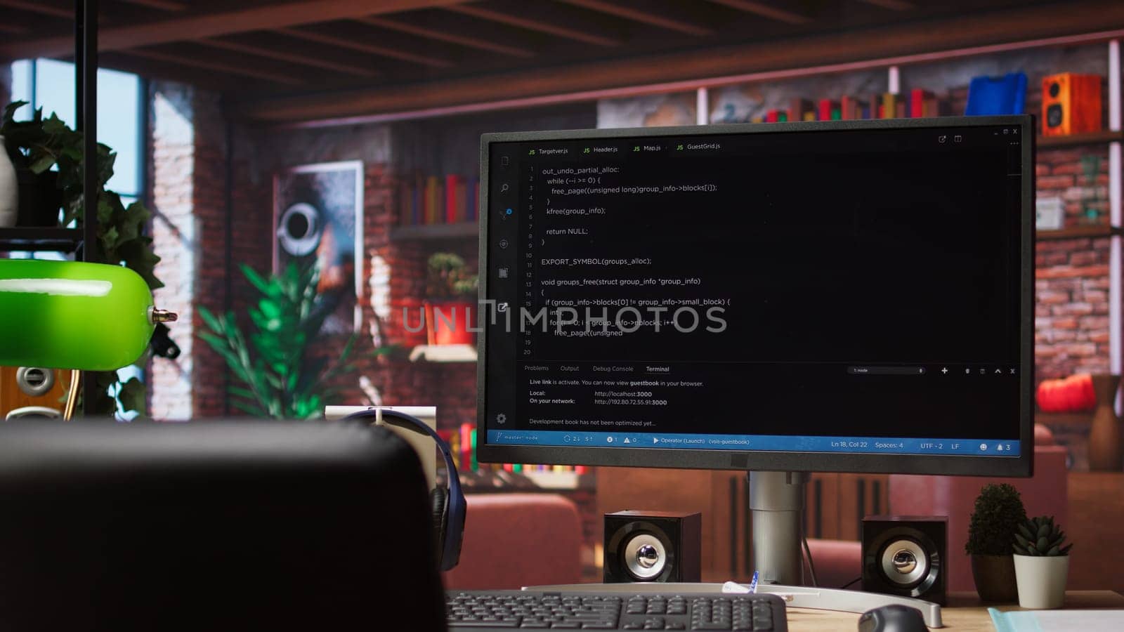 Computer desk with coding application on monitor used for creating software, implementing algorithms. Code editor on PC display used to build applications in cozy bright living room