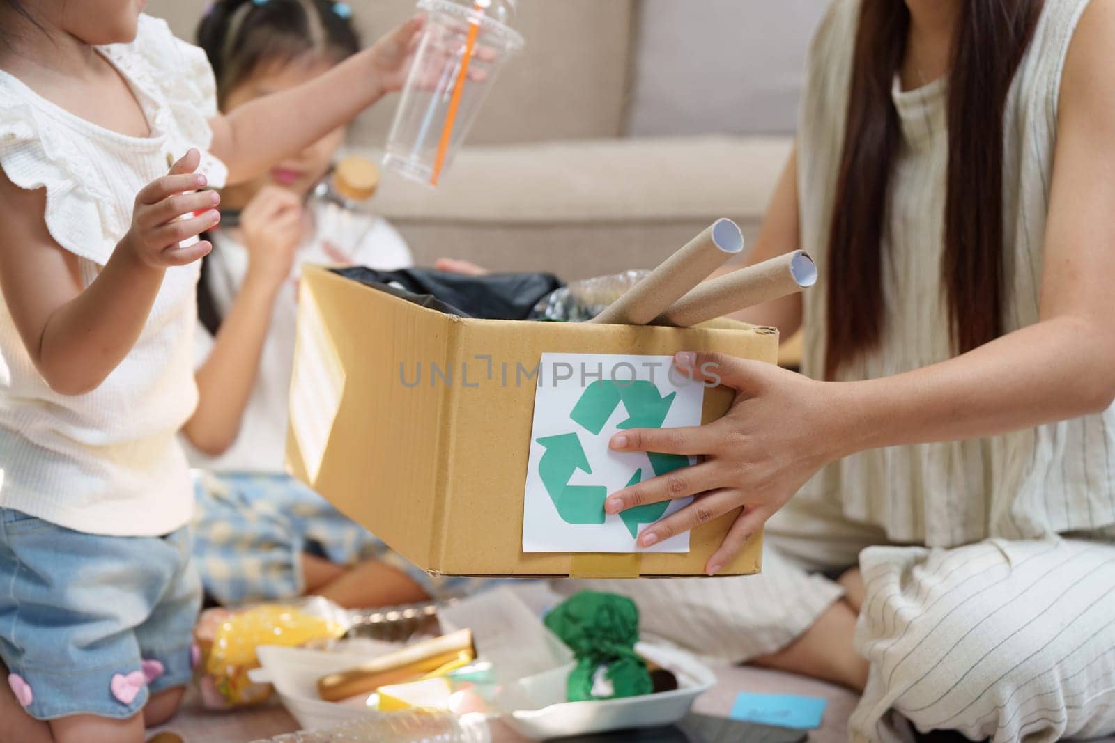 A mother guides her children in sorting recyclable materials, emphasizing the importance of recycling and responsible waste management at home.