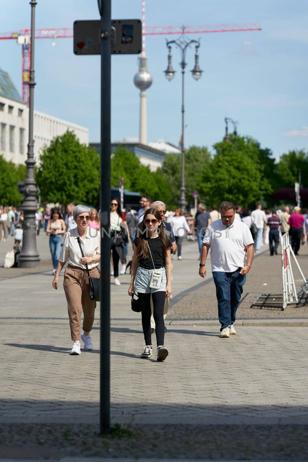 Berlin, Germany – May 01, 2025: Tourists on Pariser Platz in front of the Brandenburg Gate in the center of Berlin. The television tower in the background.