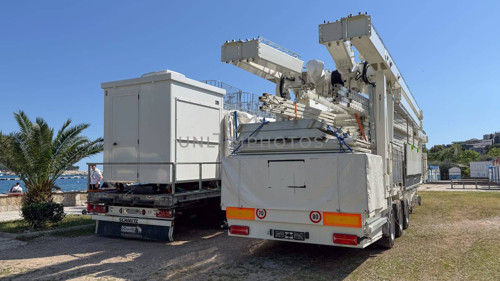 Budva, Montenegro - May 18, 2025: Ferris wheel cabins are folded on truck beside scenic waterfront view