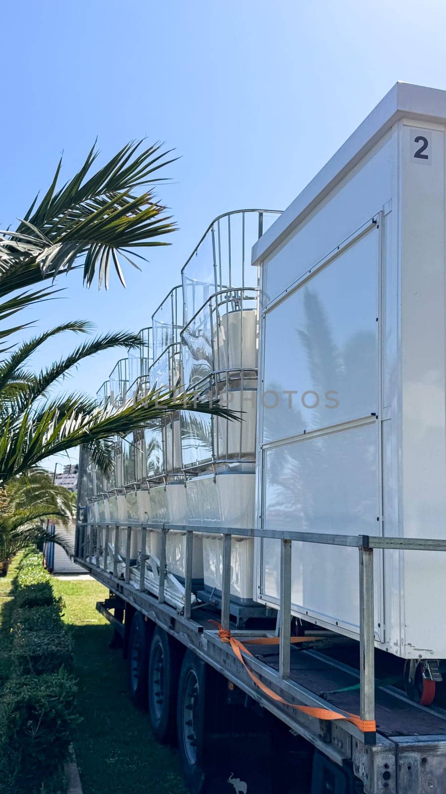 Budva, Montenegro - May 18, 2025: Ferris wheel cabins are folded and arranged on a trailer surrounded by palm trees