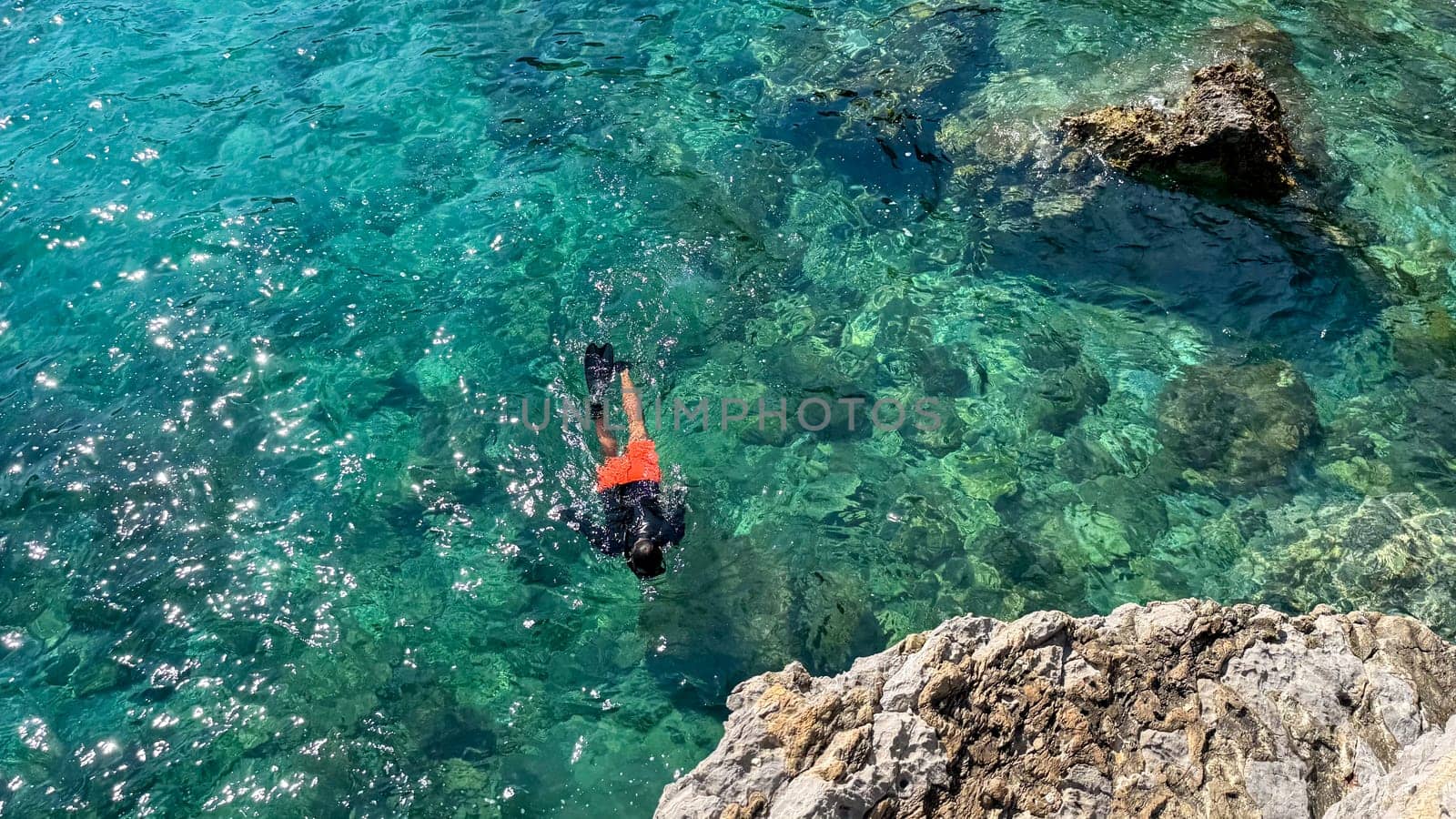 Budva, Montenegro - May 18, 2025: Male snorkeler explores vibrant underwater world near rocky coast