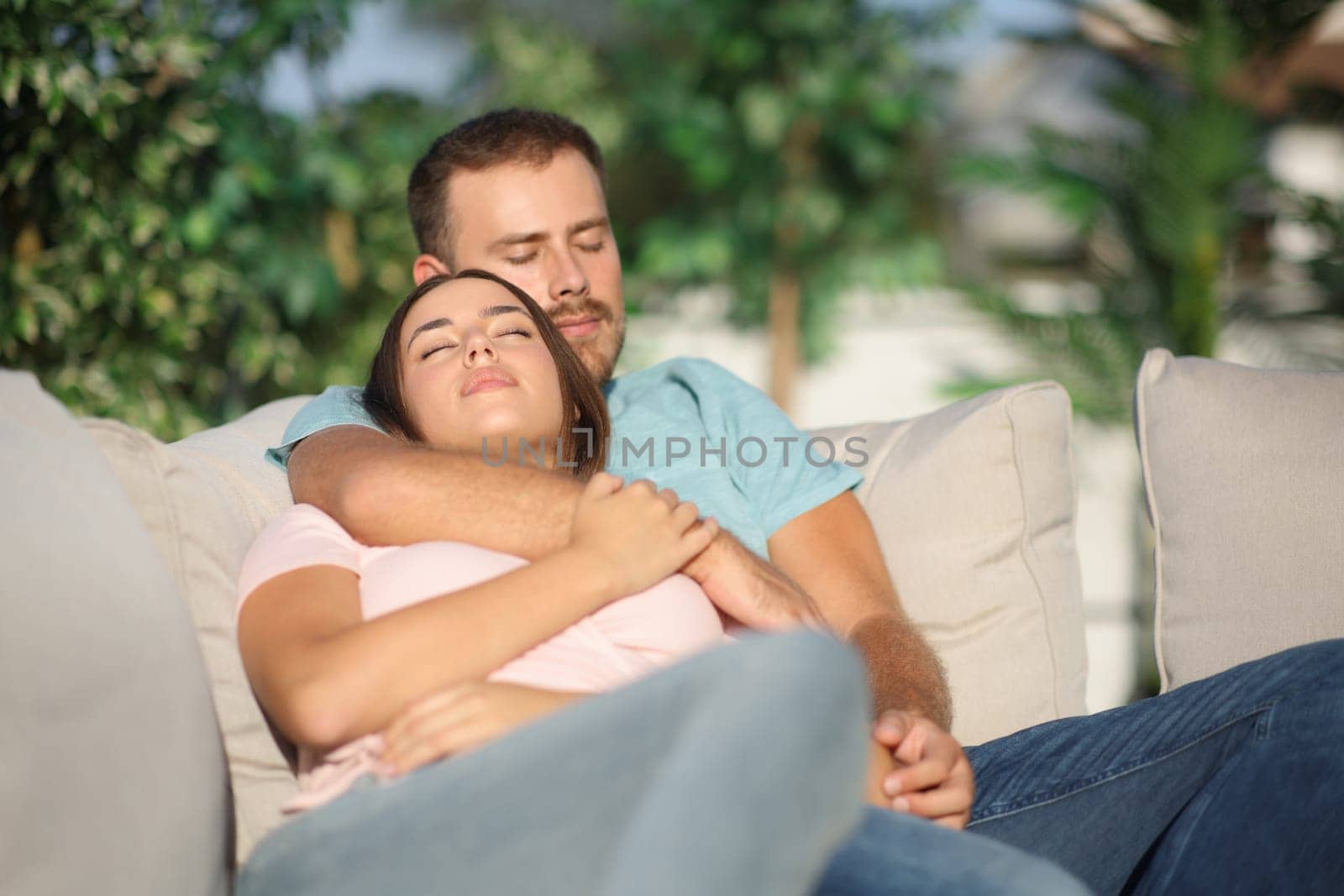 Couple sleeping sitting in a comfortable exterior sofa in a terrace at home