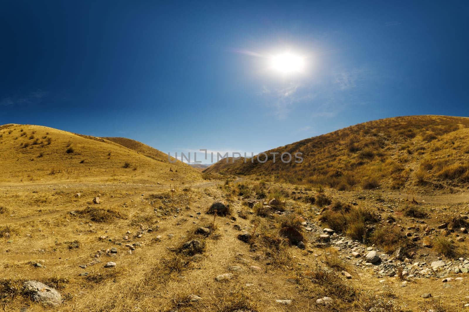dry river bed between hills and clear blue sky above at sunny autumn day