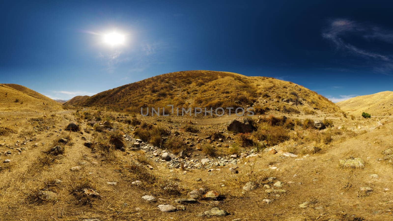 dry river bed between hills and clear blue sky above at sunny autumn day