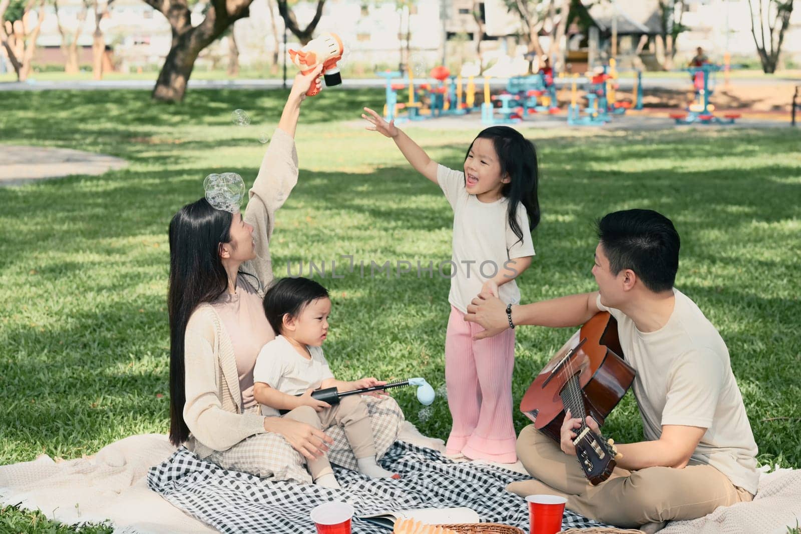 Happy family playing with bubbles during a picnic in the park.