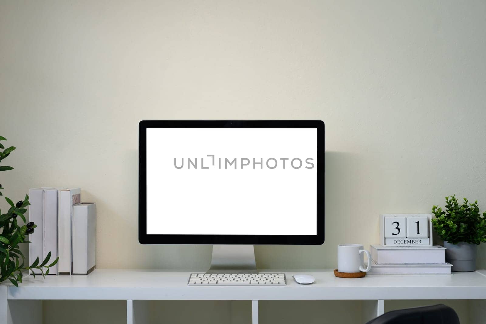 Minimal home office with desktop monitor on white desk with calendar.