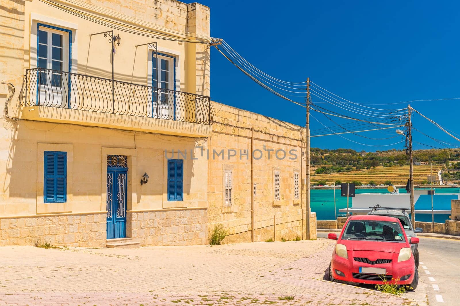 A typical Maltese house with a red car parked in front of it, Marsaxlokk, Malta.