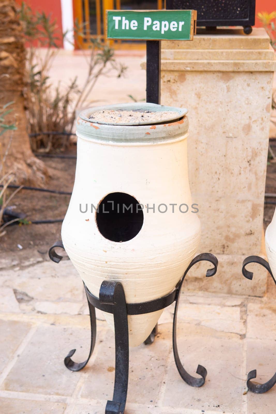 Decorative bin for paper waste outdoors with a sign. Concept of waste sorting and recycling for public areas. Environmental responsibility and sustainable practice promoting eco-friendly disposal