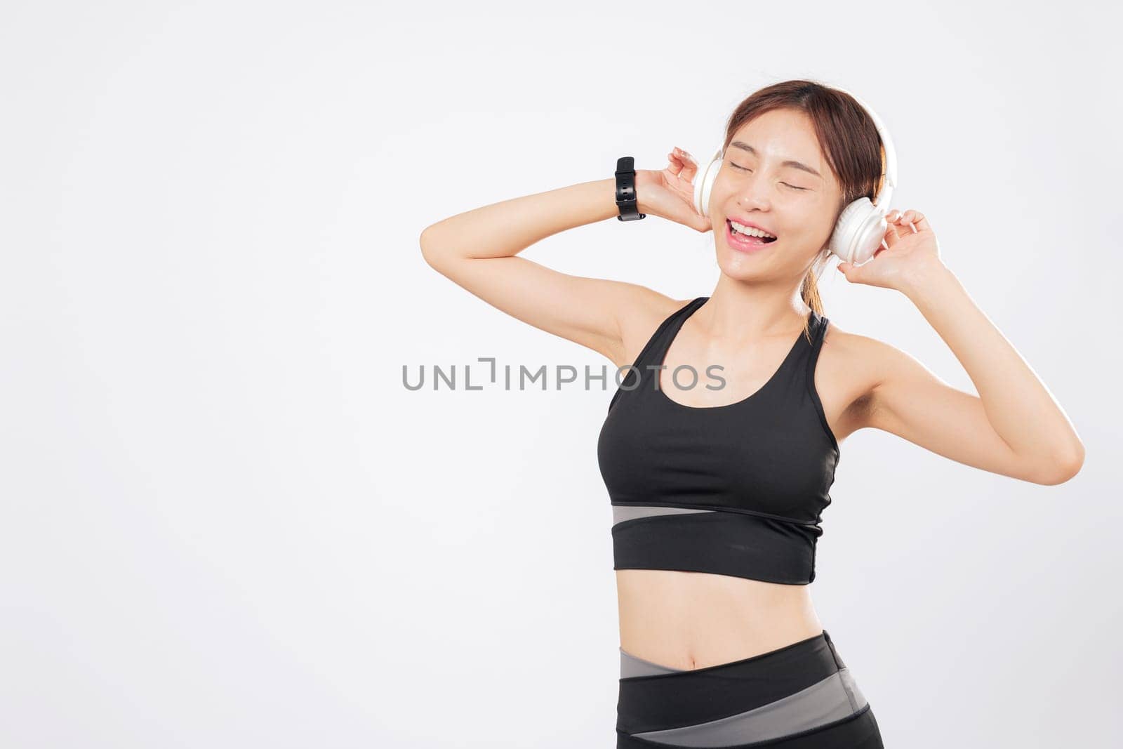 Dance expresses freedom for this cheerful Asian woman in workout gear. As music flows, she moves again to dance with confidence and a smile on her face. isolated studio white background
