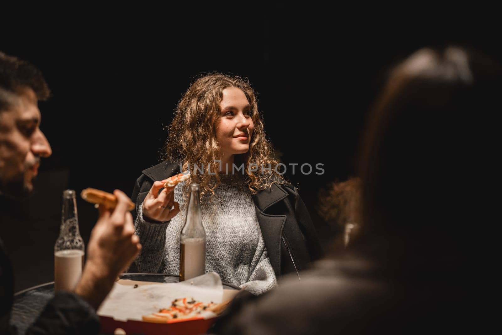 A group of friends shares a joyful moment, celebrating friendship over pizza and drinks. The atmosphere is relaxed, highlighting camaraderie and good food in a cozy environment.