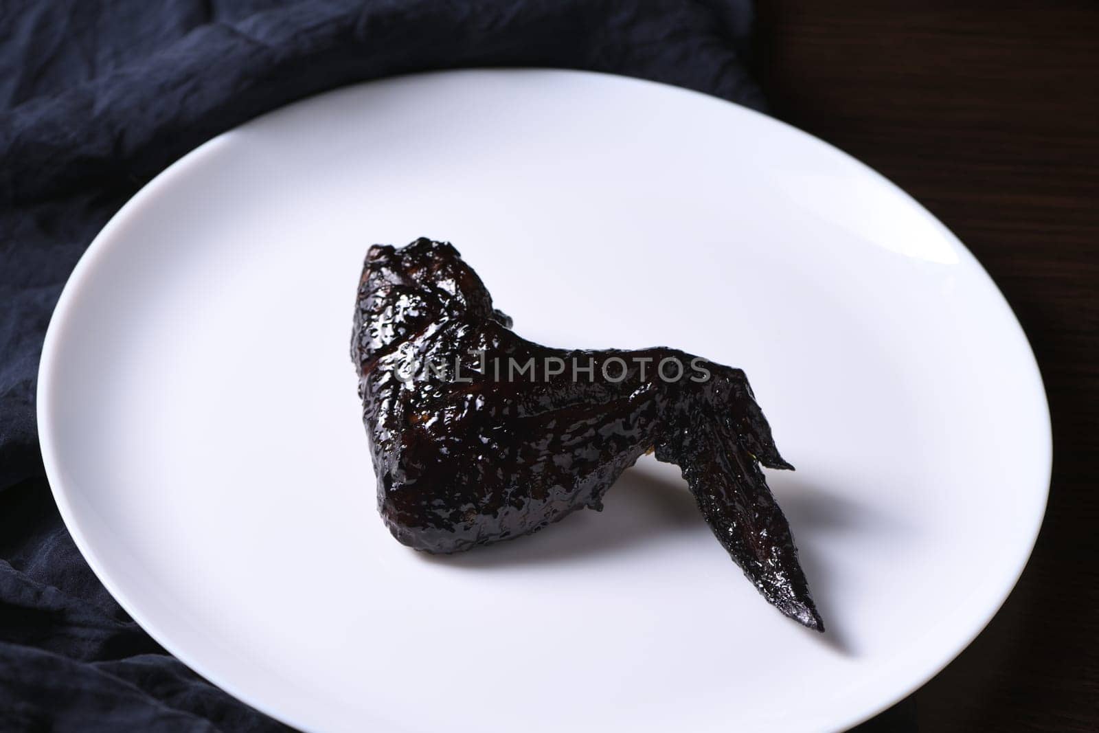 Bat wings. Cooked in sweet and sour sauce with cuttlefish ink, served with ketchup on a plate. An original idea for a Halloween party