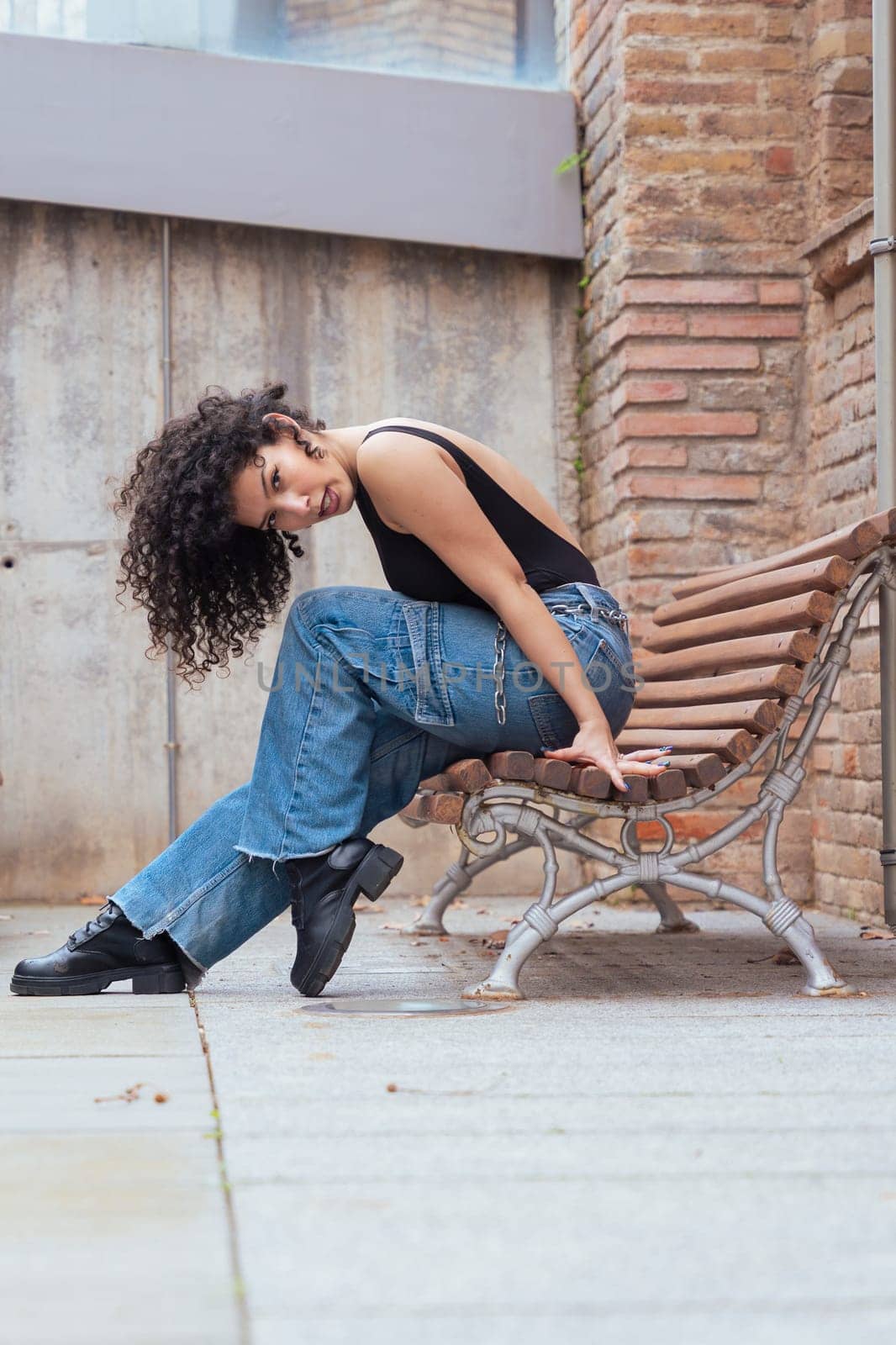 African American woman dancing in a creative pose between benches in an urban setting. he wears casual clothes and shows balance,strength, and expression. Concept of movement, art,and freedom.Vertical