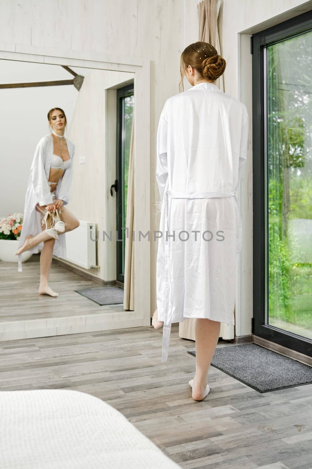 Stylish woman looking at her reflection in large wall mirror while dressing