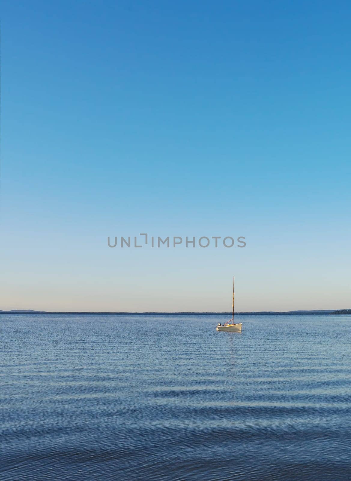 Background of a marine or aquatic environment with one small sailing boat afloat on Lake Cootharaba, Queensland, on an Autumn day.
