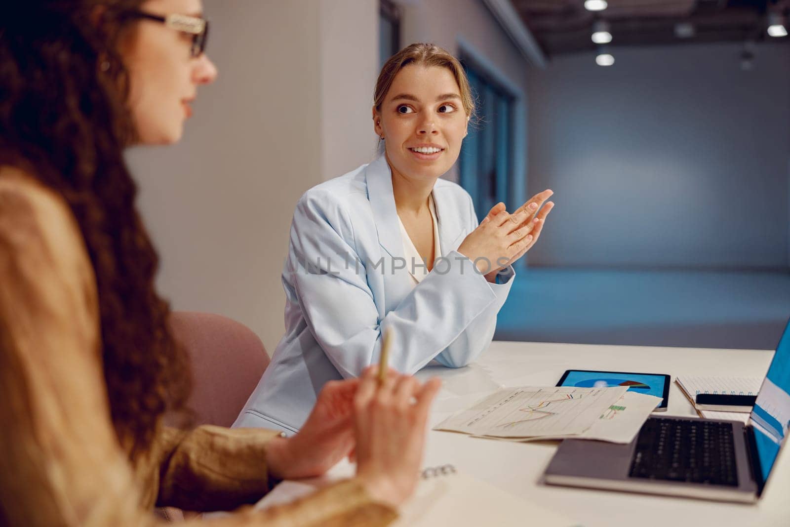 In a contemporary office environment, two skilled professional women are engaged in a discussion about ideas