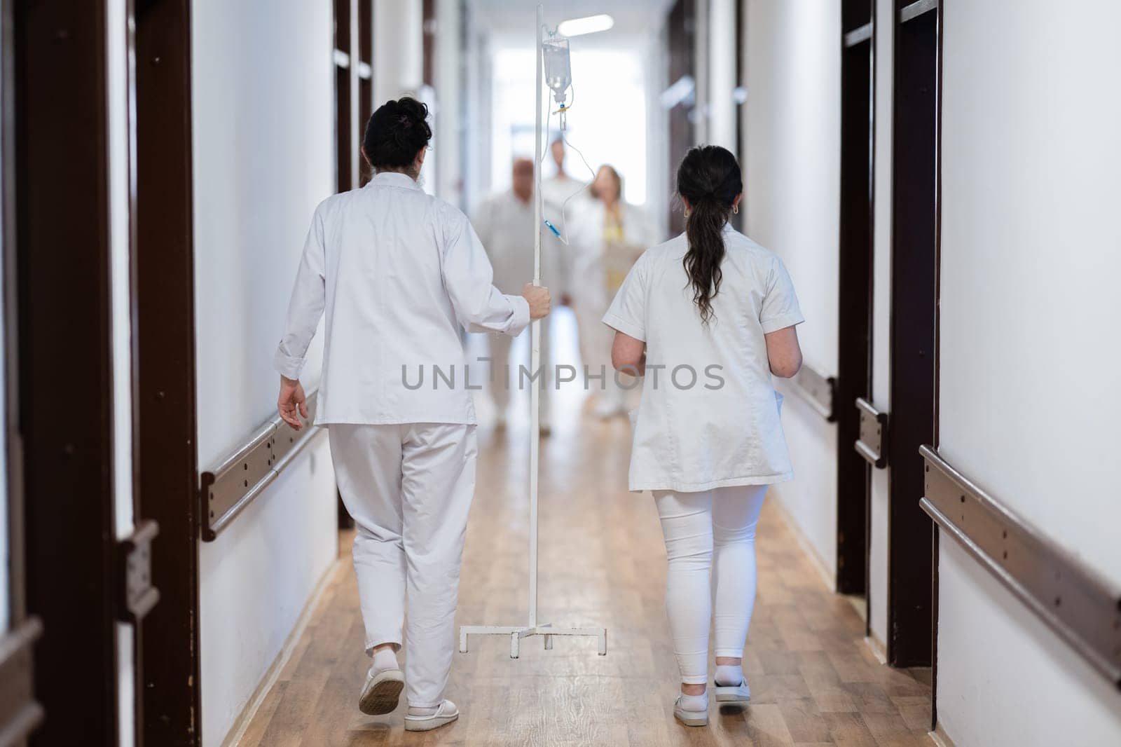 Medical personnel, including doctors and nurses, urgently respond in a busy hospital hallway, showcasing their quick action and teamwork in a critical situation