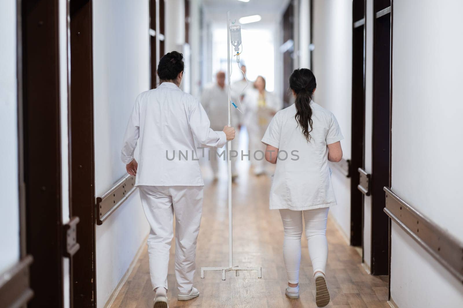 A group of healthcare professionals in white uniforms walking through a hospital hallway while reviewing patient documents and discussing treatment plans