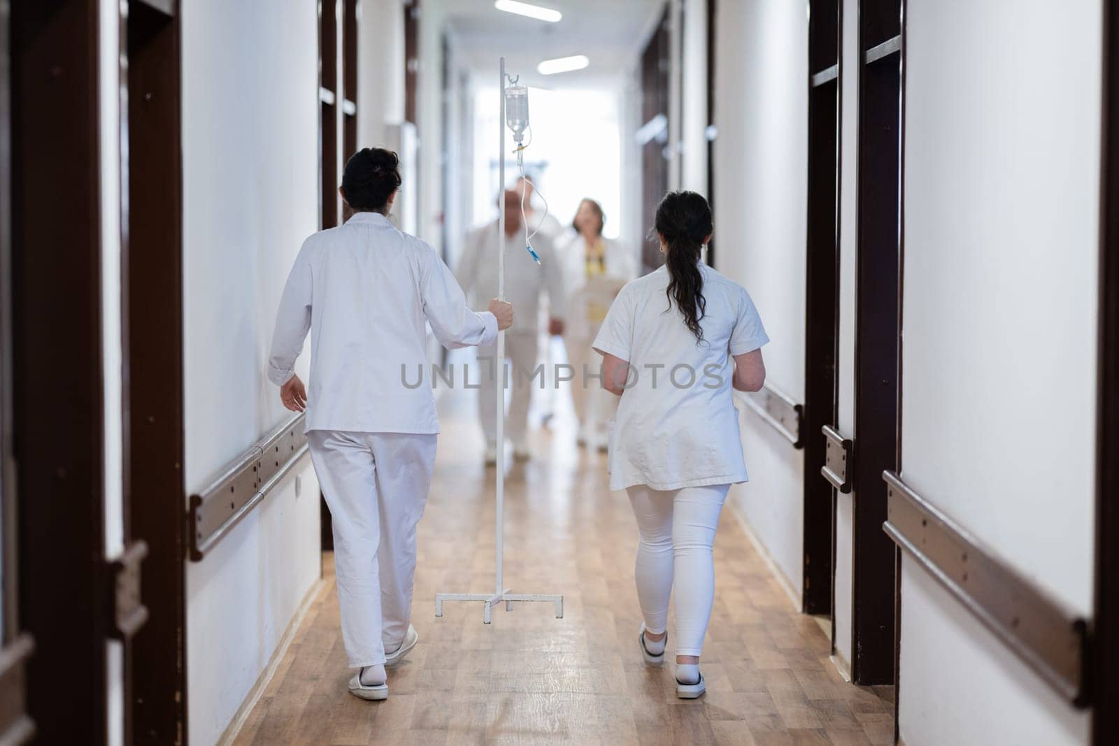 Medical personnel, including doctors and nurses, urgently respond in a busy hospital hallway, showcasing their quick action and teamwork in a critical situation