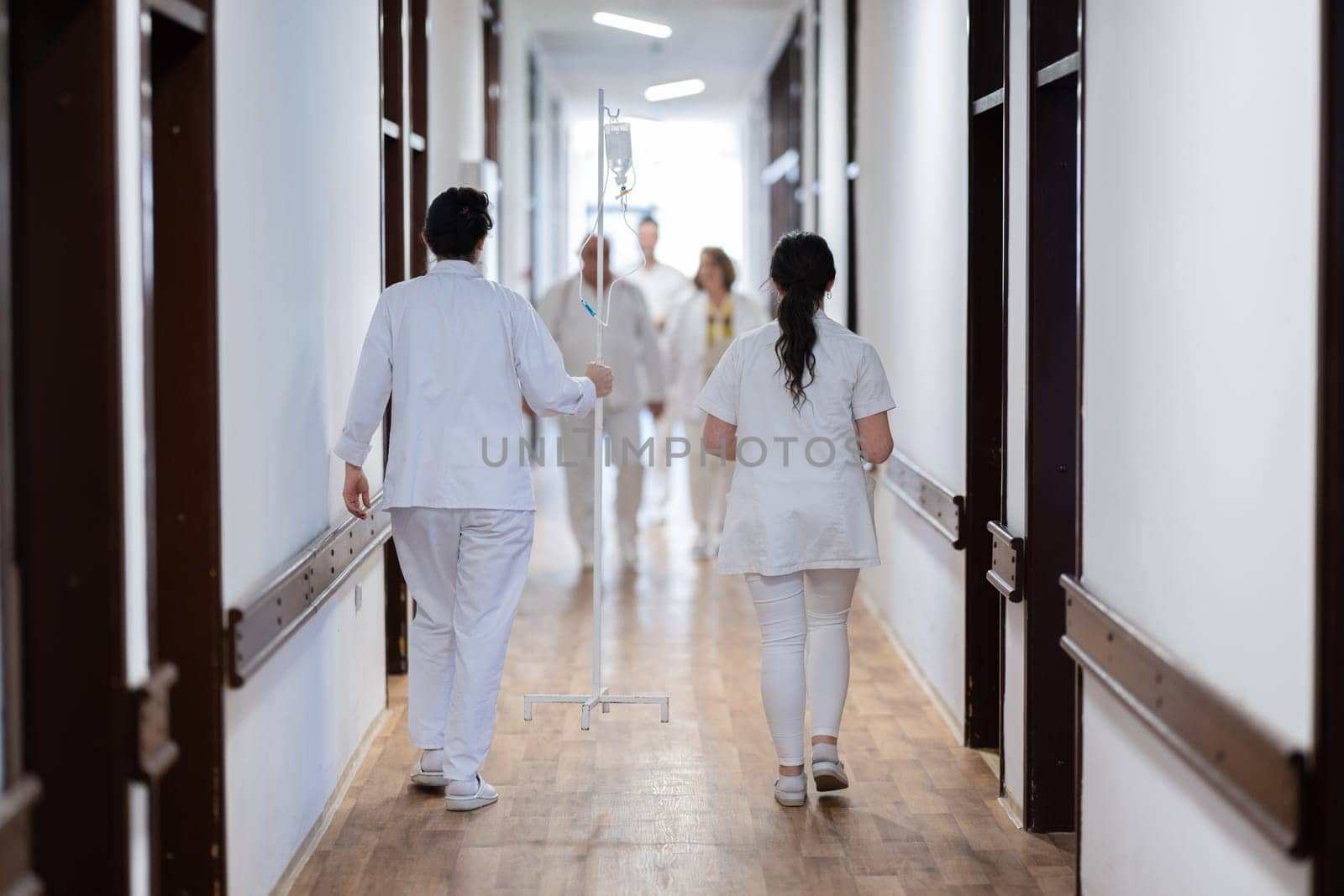 A group of healthcare professionals in white uniforms walking through a hospital hallway while reviewing patient documents and discussing treatment plans