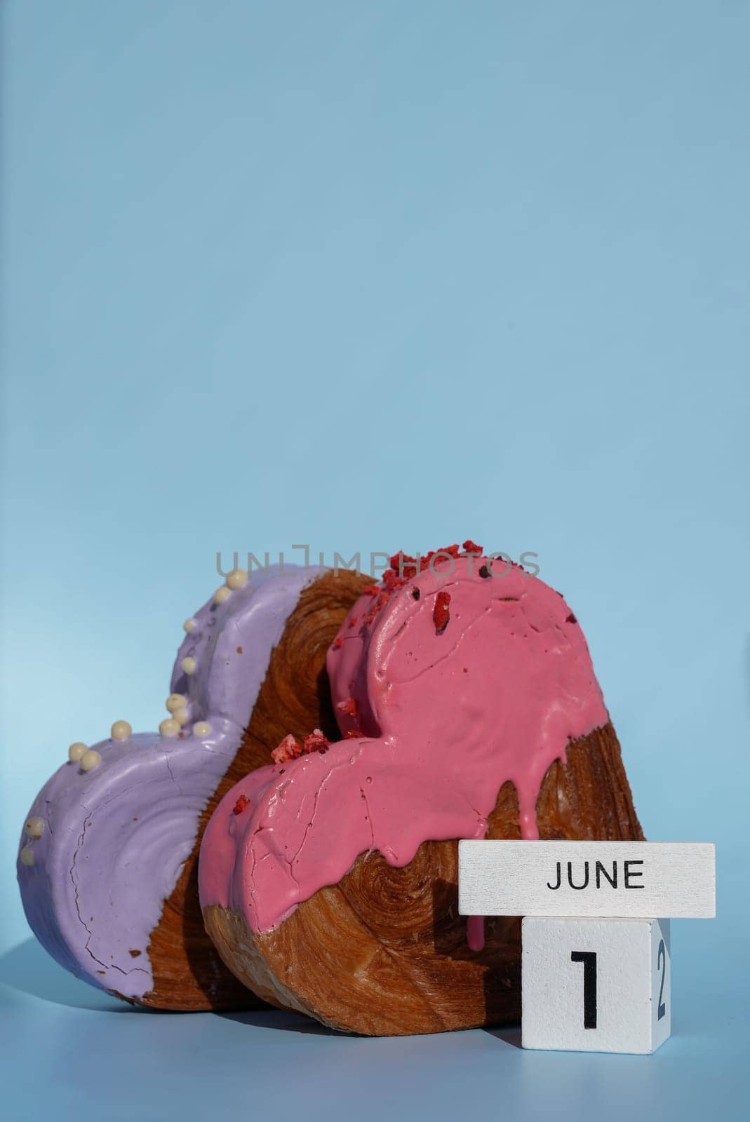 1 June International Children's day celebration greeting card Heart shaped two croissants on blue background with copy space. Puff pastry new trendy sweet dessert bakery. Creamy dough experiment