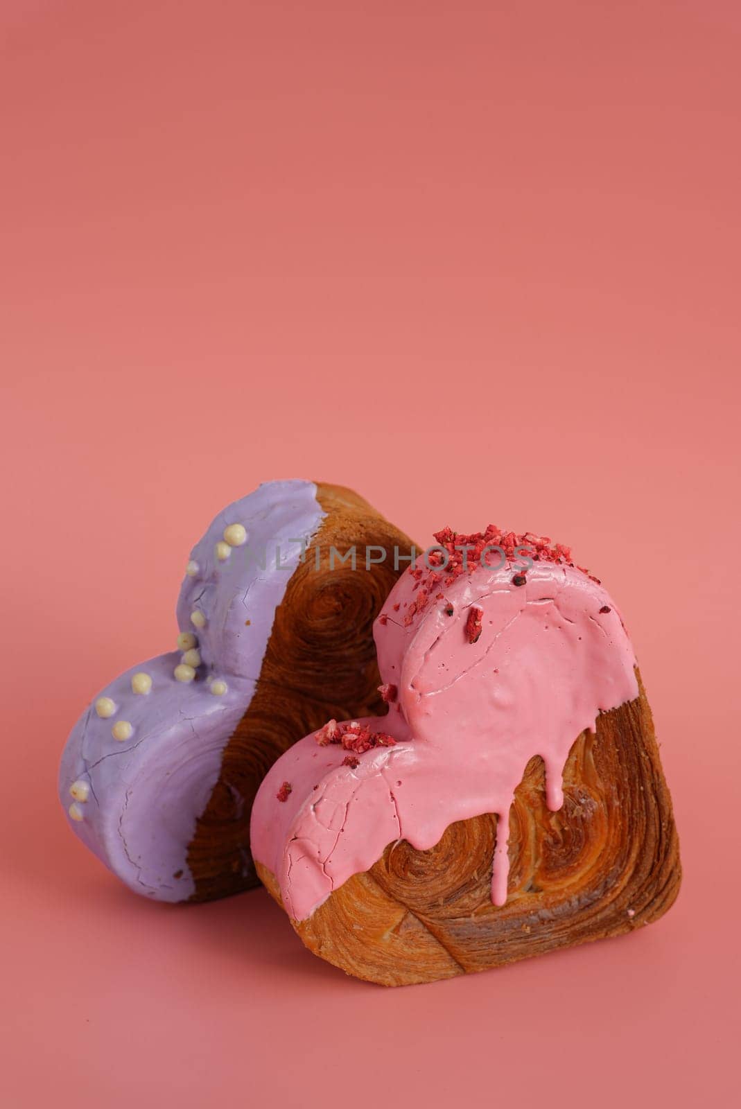 Heart shaped two couple croissants on pink background with copy space. Puff pastry new trendy sweet dessert bakery. Creamy dough experiment