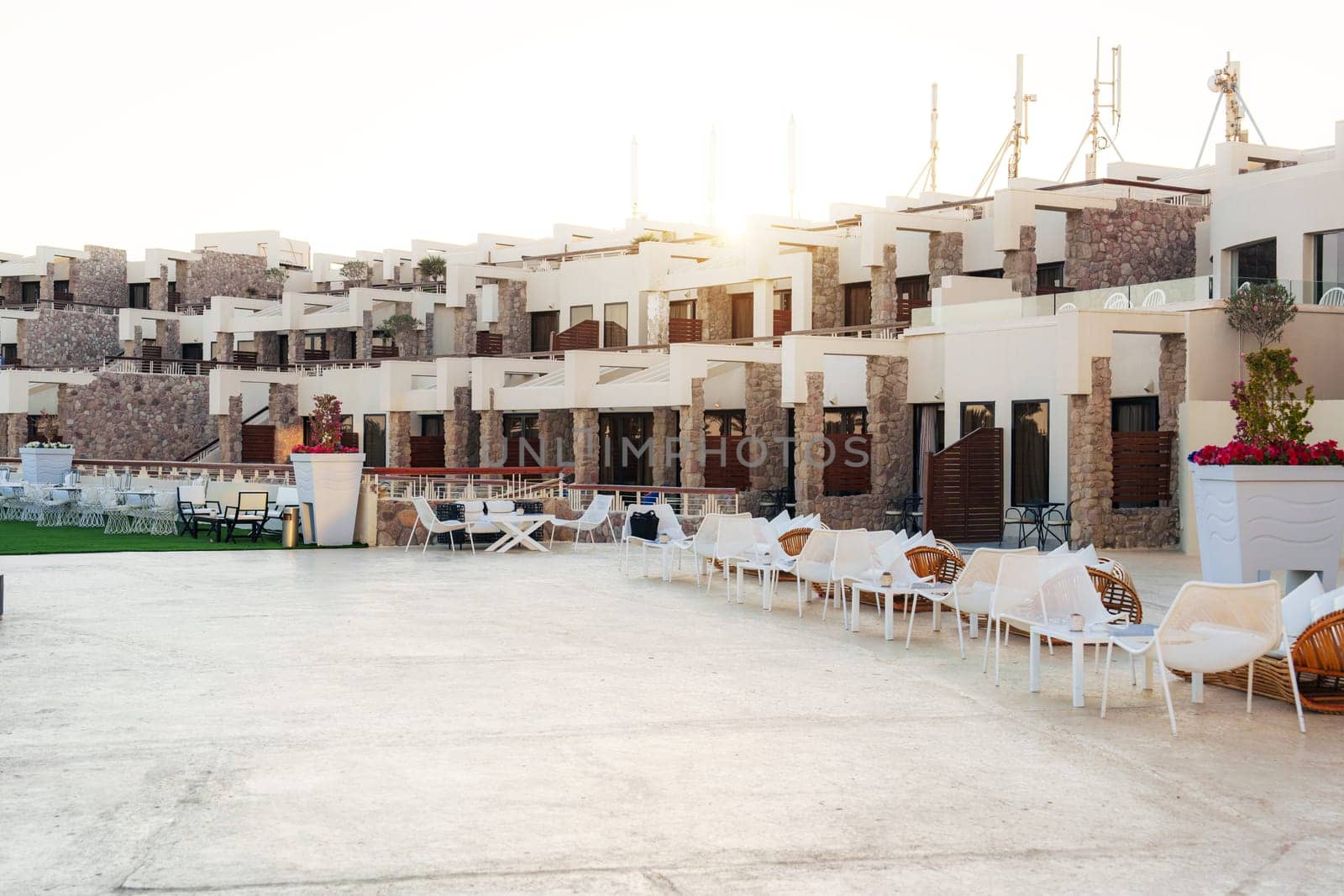 Luxurious resort complex with contemporary design showcases elegant outdoor seating and a beautifully landscaped area under a clear sky at sunset.