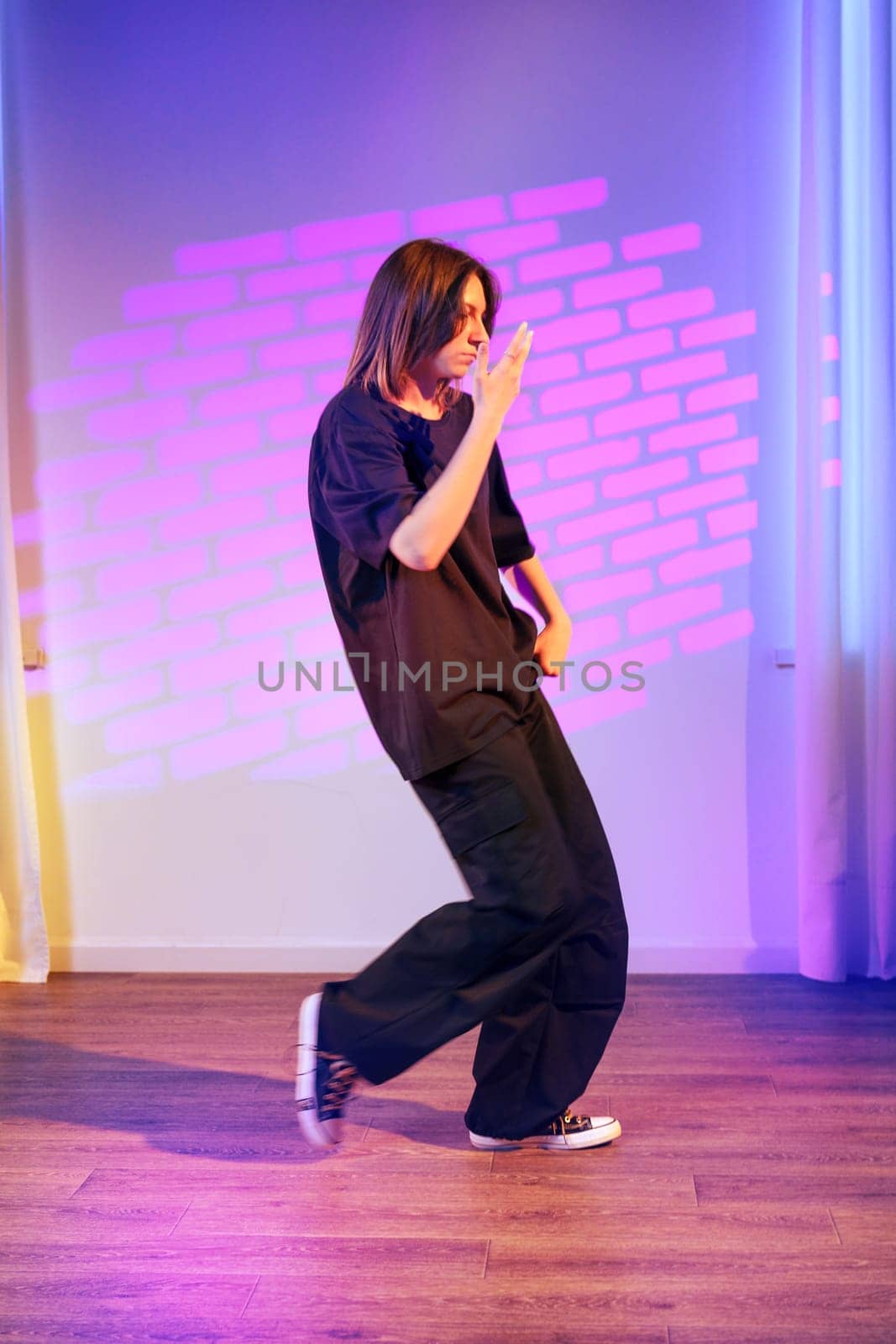 A dancer showcases skillful movements in a dynamic routine within a contemporary studio. The vibrant lighting adds flair to the energetic atmosphere.
