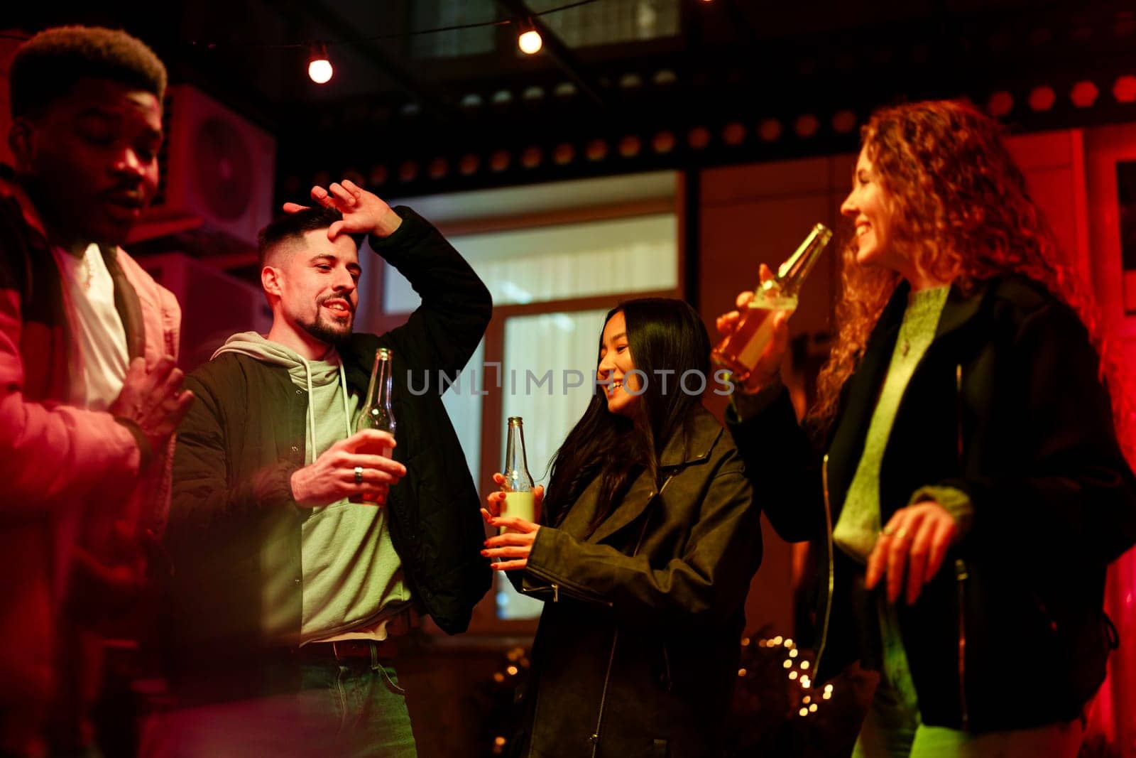 Four friends celebrate in a vibrant space, sharing laughter and drinks under colorful lights. The atmosphere is joyful, capturing the essence of companionship at night.