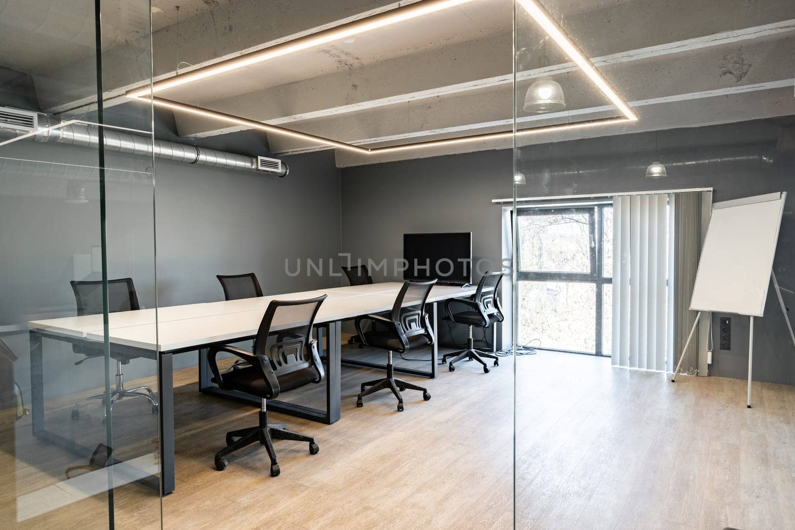 A spacious conference room features sleek furniture, a large table, ergonomic chairs, and ample natural light illuminating the space through glass walls.