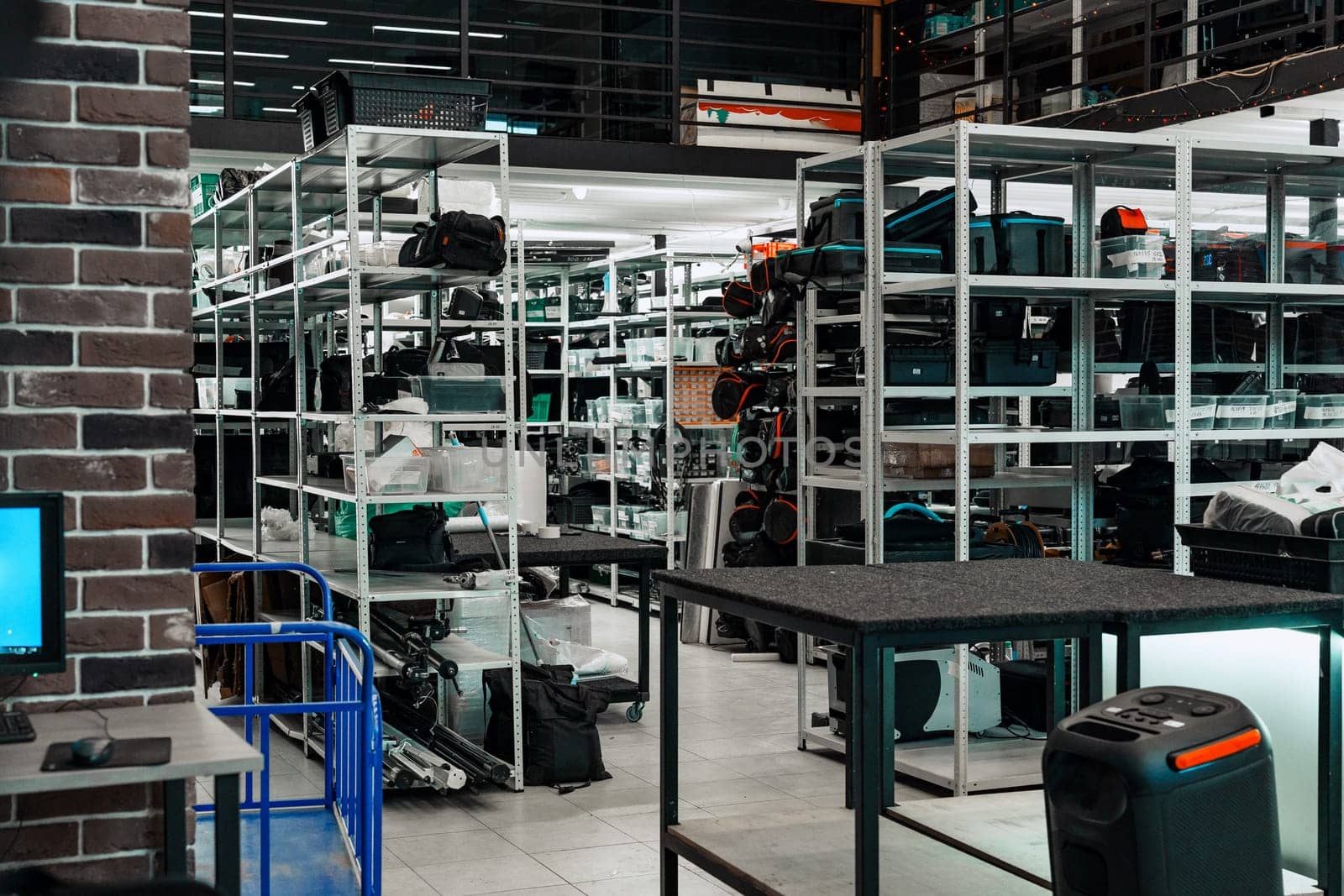 Shelves are stocked with various equipment and supplies in a spacious warehouse. The bright interior is bustling with activity, providing a sense of order and efficiency.