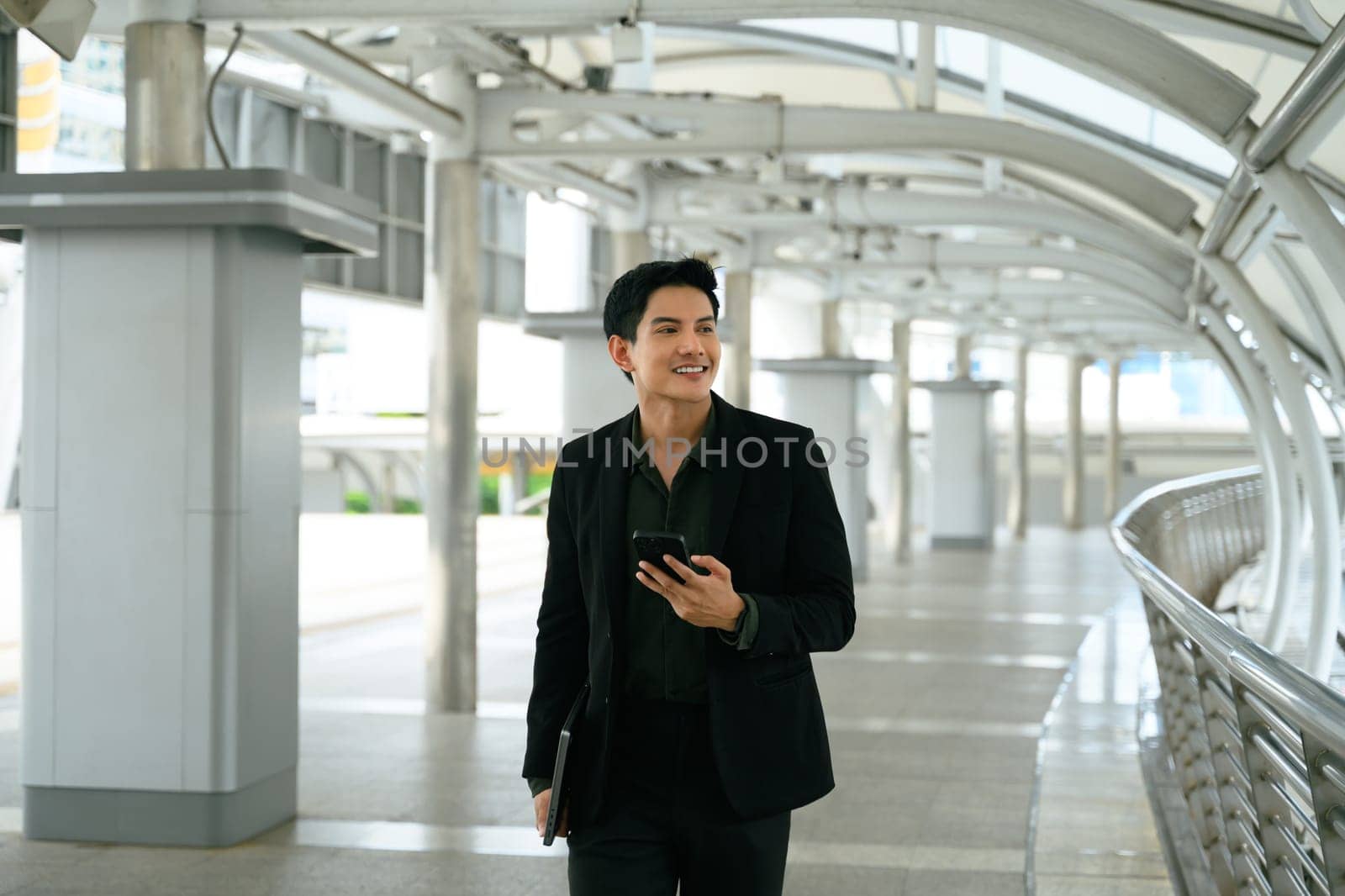 Smiling adult businessman with a phone in hand commuting to work.
